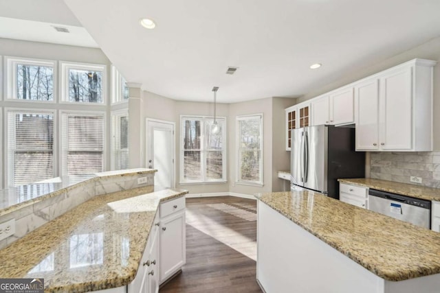 kitchen with white cabinets, appliances with stainless steel finishes, dark wood-type flooring, hanging light fixtures, and light stone counters