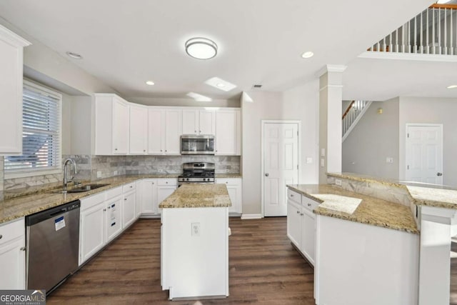 kitchen with sink, white cabinets, light stone countertops, a center island, and stainless steel appliances