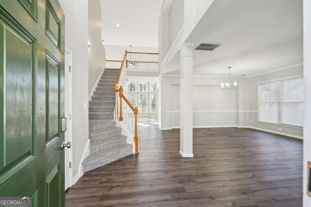 foyer entrance with decorative columns, ornamental molding, an inviting chandelier, and dark hardwood / wood-style flooring