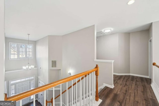 hall with dark hardwood / wood-style floors and a chandelier