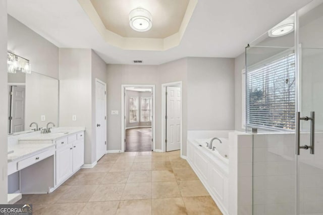 bathroom with tile patterned floors, vanity, a raised ceiling, and shower with separate bathtub