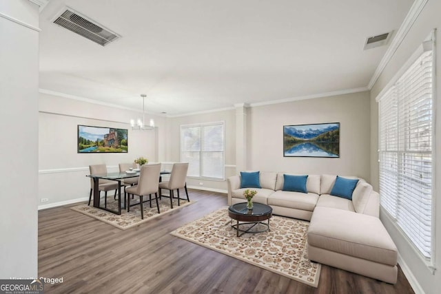 living room with dark hardwood / wood-style floors, crown molding, and a notable chandelier