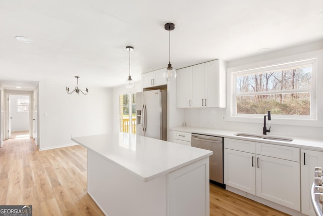 kitchen with a center island, white cabinets, sink, pendant lighting, and stainless steel appliances