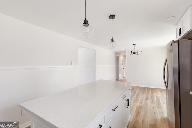 kitchen featuring white cabinets, a center island, hanging light fixtures, and stainless steel refrigerator