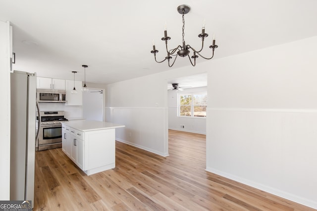 kitchen with decorative light fixtures, white cabinets, a center island, and appliances with stainless steel finishes