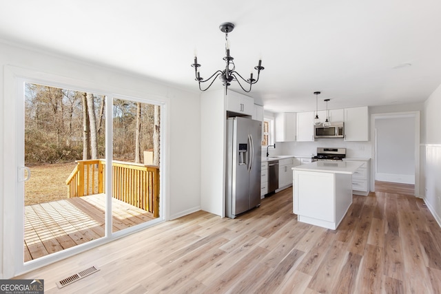 kitchen with a center island, appliances with stainless steel finishes, white cabinets, decorative light fixtures, and sink