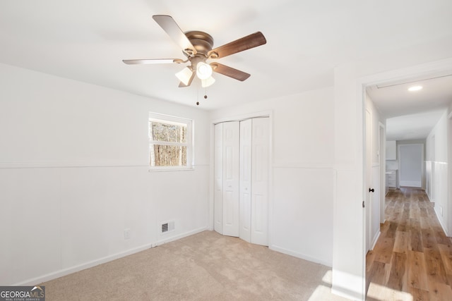 unfurnished bedroom with light carpet, a closet, and ceiling fan