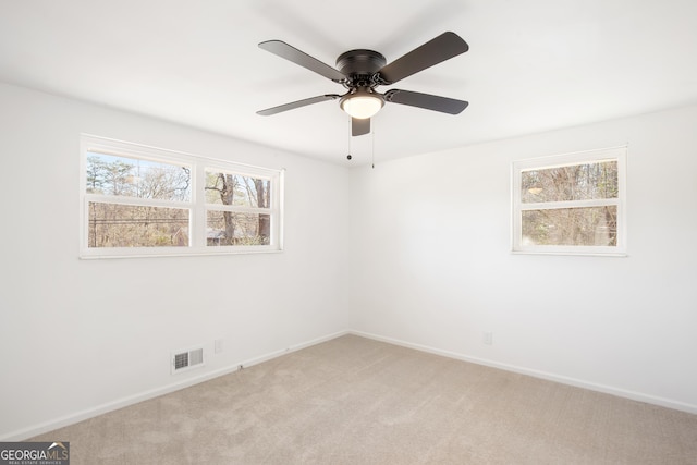 empty room with ceiling fan and light carpet