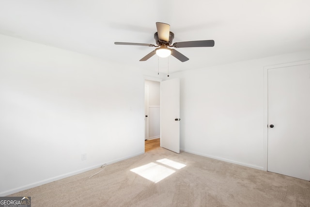 spare room with ceiling fan and light colored carpet