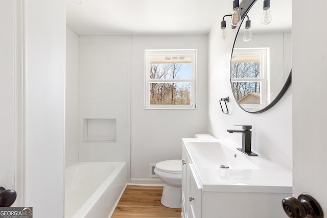 bathroom with wood-type flooring, a healthy amount of sunlight, toilet, and vanity