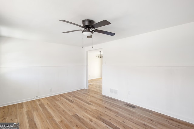 spare room with light wood-type flooring and ceiling fan with notable chandelier