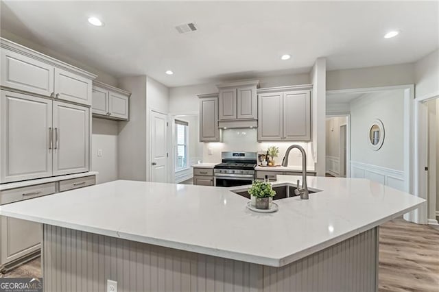 kitchen featuring stainless steel range oven, sink, gray cabinets, and a large island