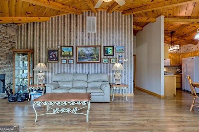 unfurnished living room featuring ceiling fan, light wood-type flooring, and a high ceiling