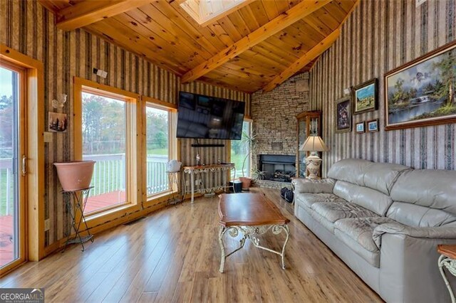 unfurnished living room with plenty of natural light, light wood-type flooring, wood ceiling, and a skylight