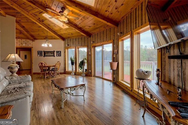 living room with wood ceiling, vaulted ceiling with skylight, ceiling fan with notable chandelier, and light hardwood / wood-style floors