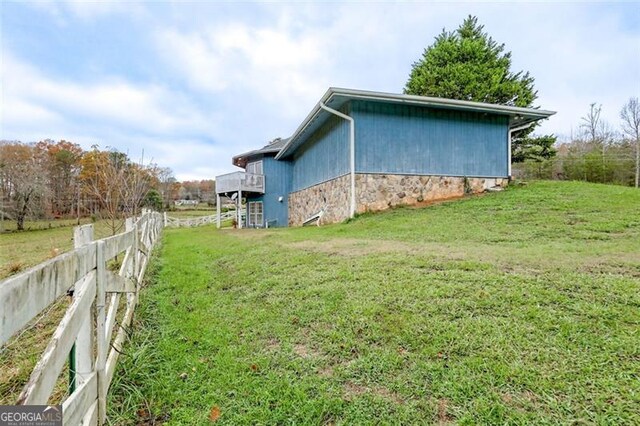 view of side of home featuring a rural view and a lawn