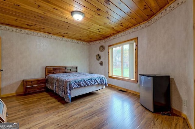 bedroom with wood-type flooring, wooden ceiling, and stainless steel fridge