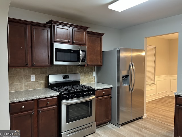 kitchen featuring dark brown cabinets, light hardwood / wood-style flooring, appliances with stainless steel finishes, and tasteful backsplash