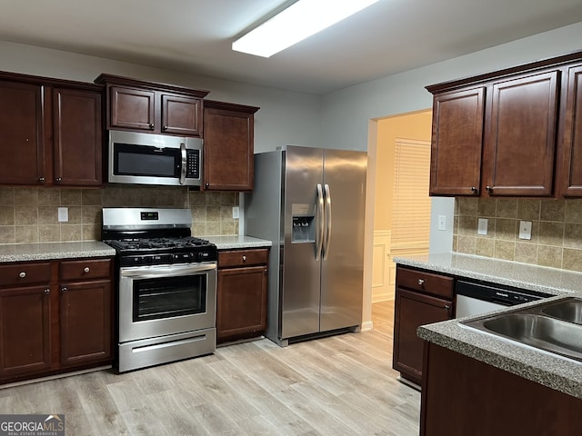 kitchen with sink, light hardwood / wood-style floors, dark brown cabinetry, and appliances with stainless steel finishes