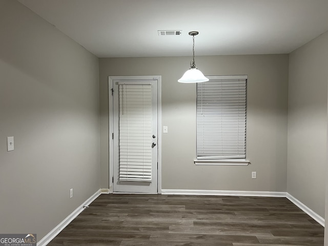 unfurnished dining area with dark wood-type flooring