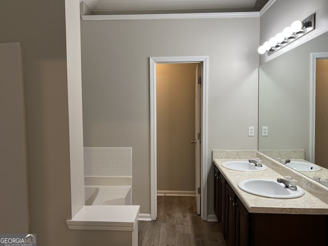 bathroom featuring hardwood / wood-style flooring, a tub to relax in, vanity, and crown molding