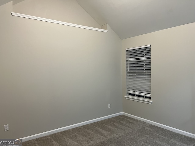 unfurnished room with dark carpet and lofted ceiling