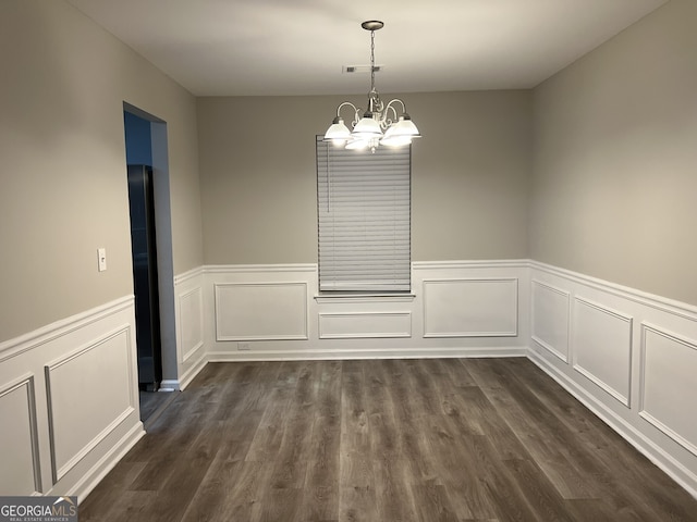 unfurnished dining area with an inviting chandelier and dark hardwood / wood-style floors