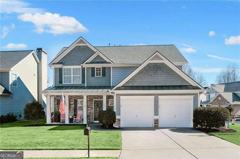 craftsman-style home featuring a garage, covered porch, and a front lawn