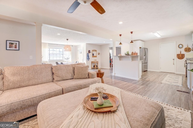 living room with light hardwood / wood-style flooring and ceiling fan