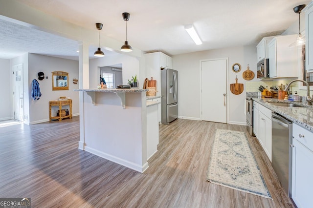 kitchen with sink, white cabinetry, appliances with stainless steel finishes, and a breakfast bar area