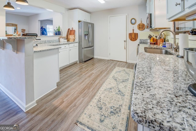 kitchen featuring sink, white cabinetry, light stone counters, and appliances with stainless steel finishes