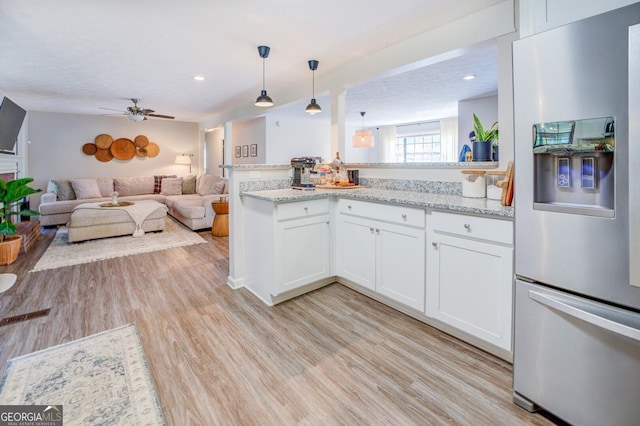 kitchen with light stone countertops, stainless steel refrigerator with ice dispenser, white cabinetry, hanging light fixtures, and light wood-type flooring