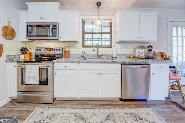 kitchen with sink, white cabinetry, light stone countertops, and appliances with stainless steel finishes