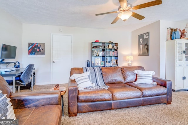 carpeted living room featuring ceiling fan and a textured ceiling