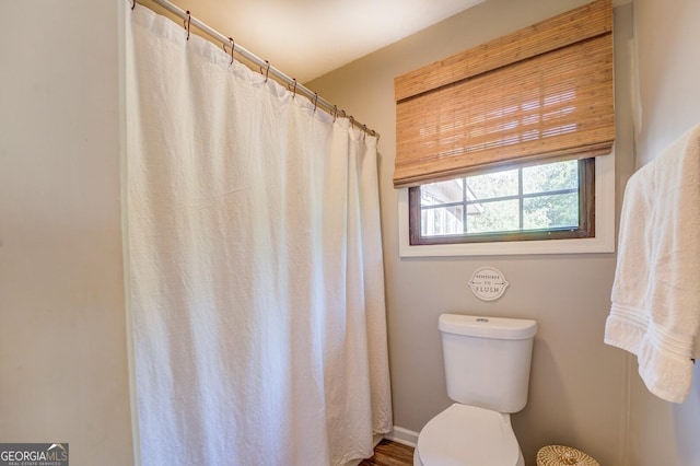 bathroom with toilet and a shower with shower curtain