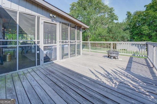 deck with an outdoor fire pit and a sunroom