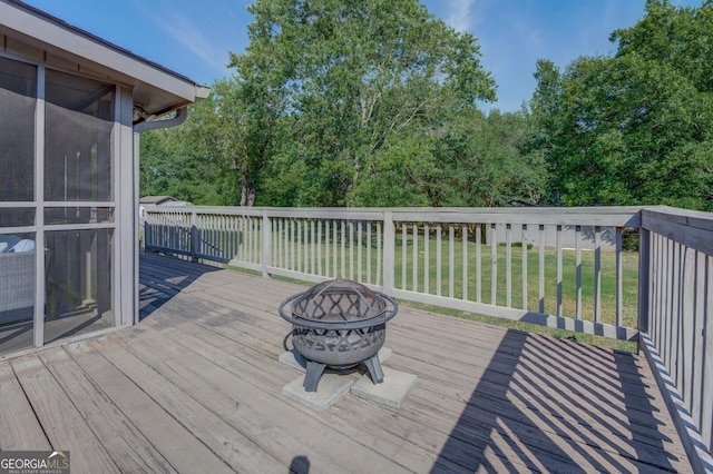 wooden deck with an outdoor fire pit and a lawn