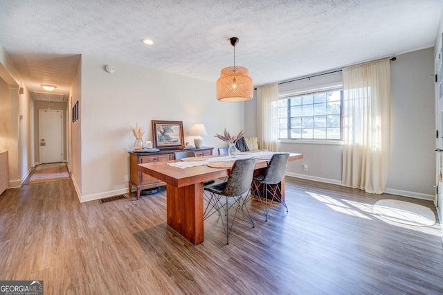 dining space featuring hardwood / wood-style flooring and a textured ceiling