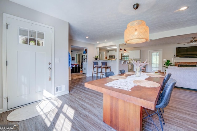 dining area with a textured ceiling, light hardwood / wood-style flooring, and ceiling fan