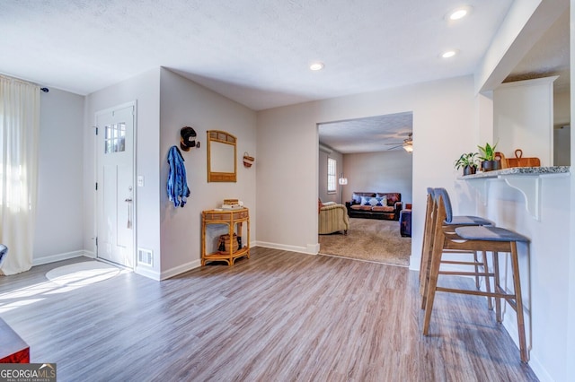 foyer entrance with ceiling fan, light hardwood / wood-style flooring, and a textured ceiling