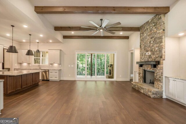 unfurnished living room featuring ceiling fan with notable chandelier, dark hardwood / wood-style flooring, crown molding, and a raised ceiling