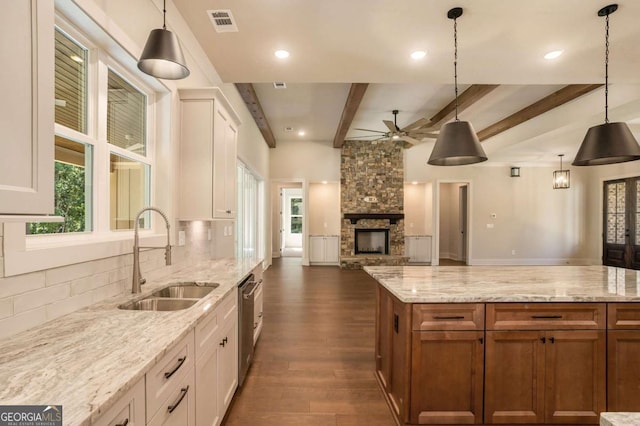 kitchen featuring sink, beamed ceiling, pendant lighting, and white cabinetry