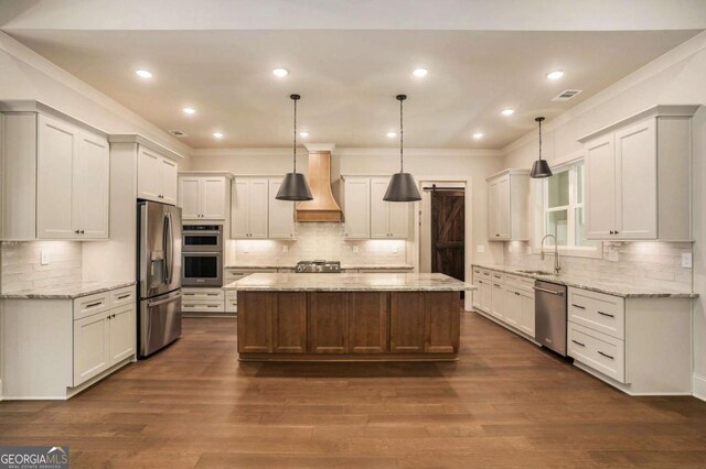 kitchen featuring pendant lighting, custom range hood, light stone counters, a center island, and stainless steel appliances