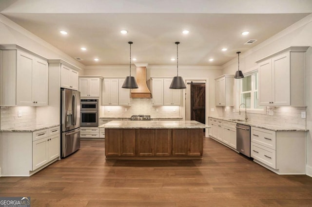 kitchen with a kitchen island, a sink, stainless steel appliances, custom range hood, and crown molding