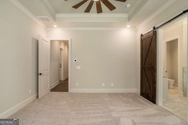 unfurnished room featuring crown molding, ceiling fan, a tray ceiling, a barn door, and carpet floors