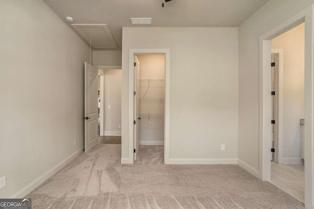 unfurnished bedroom with a walk in closet, light colored carpet, and a closet