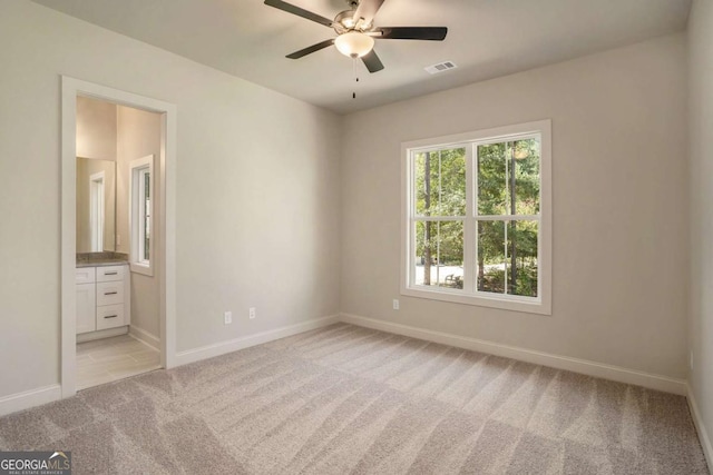 unfurnished bedroom with light carpet, visible vents, ensuite bathroom, and baseboards