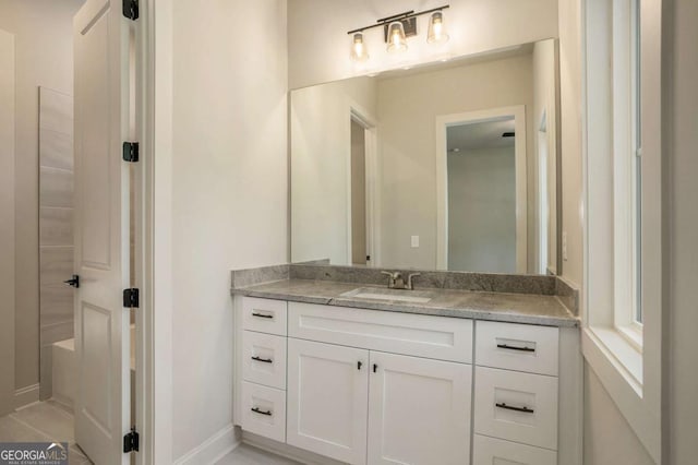 bathroom featuring a tub, baseboards, and vanity