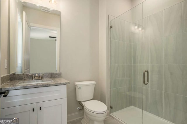 full bath with visible vents, toilet, a shower stall, baseboards, and vanity