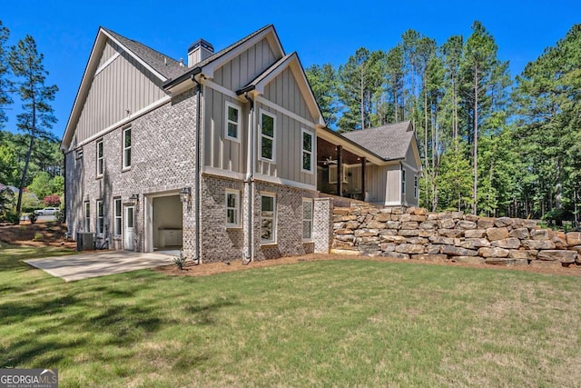 view of home's exterior with concrete driveway, a yard, brick siding, and board and batten siding